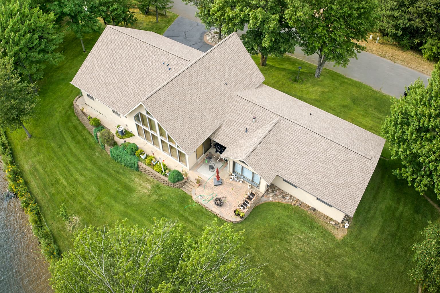 Aerial view of a completed architectural shingle roof beside a Northwoods lake